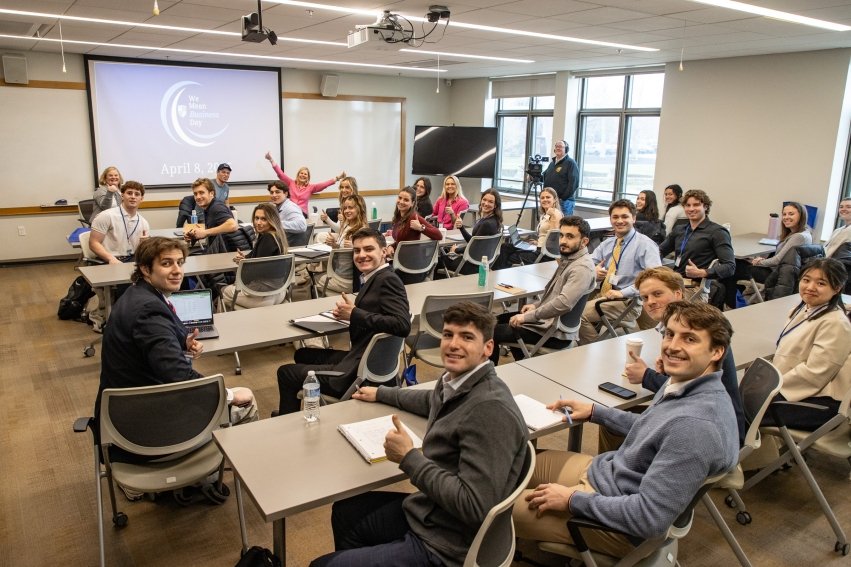Students smiling at camera during one of the breakout sessions inside of a classroom.