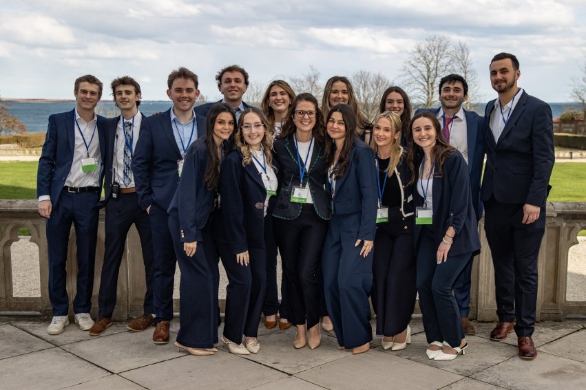 Professional group photo of the students and professor who organized We Mean Business Day, outside of Ochre Court