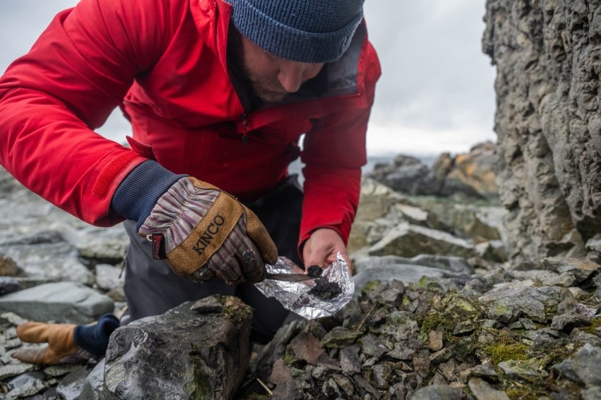 Kitchel taking a radiocarbon sample with a trowel from a firepit on Robert Island.