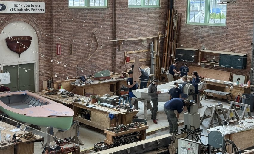 Students in the boat shop working on their wooden boat.
