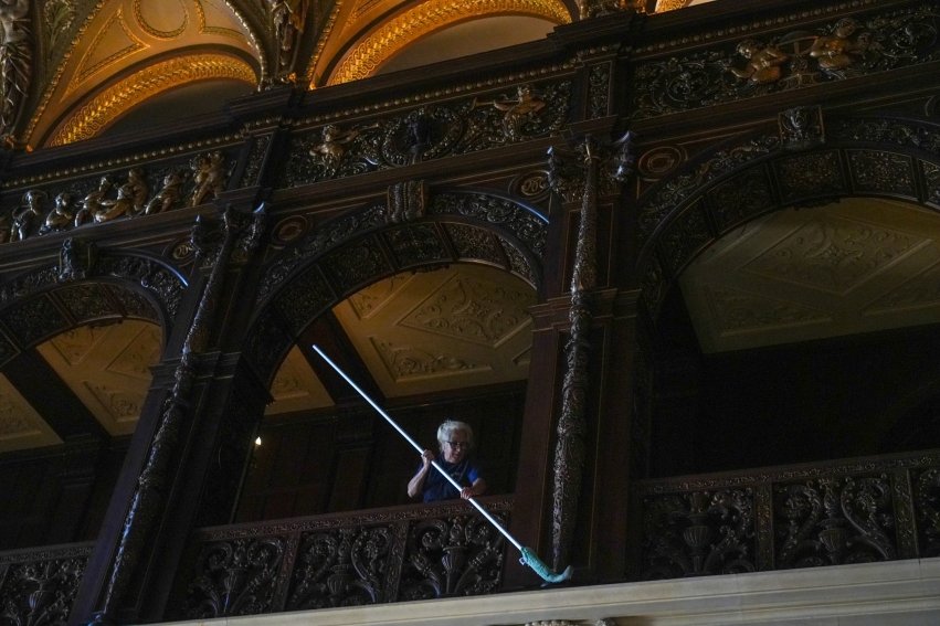 Woman cleaning the soffit of the Great Hall inside Ochre Court.