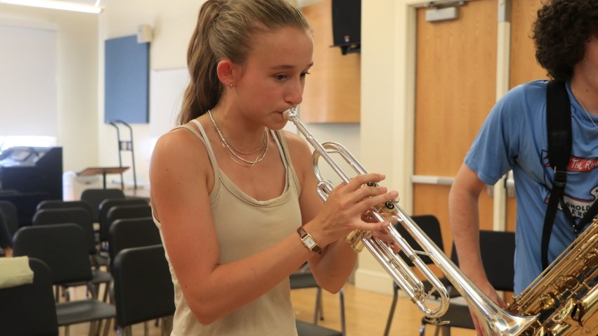 A female student playing a silver trumpet.