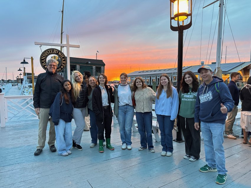 Group photo of the students and two professors at sunset at Bannisters Wharf