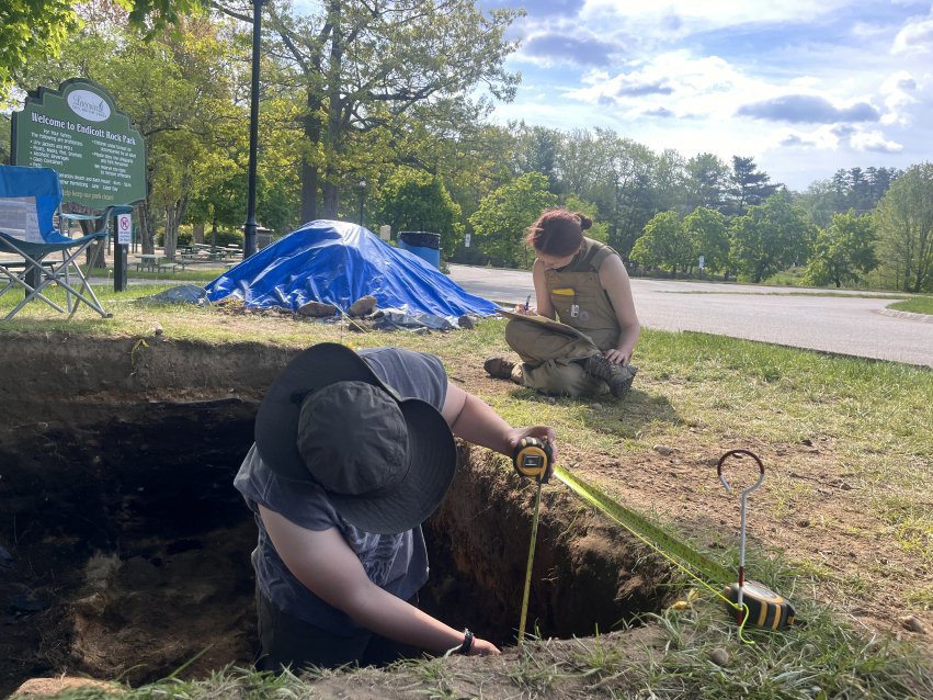 Cultural and historic preservation students measure and document an excavation unit during fieldwork at the Weirs Beach site in New Hampshire.