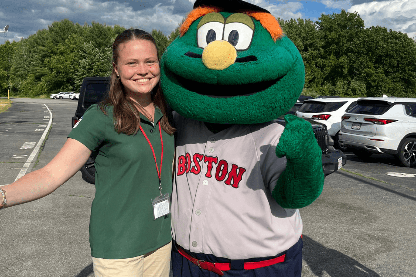 A student poses with the Boston Red Sox mascot Wally the Green Monster.