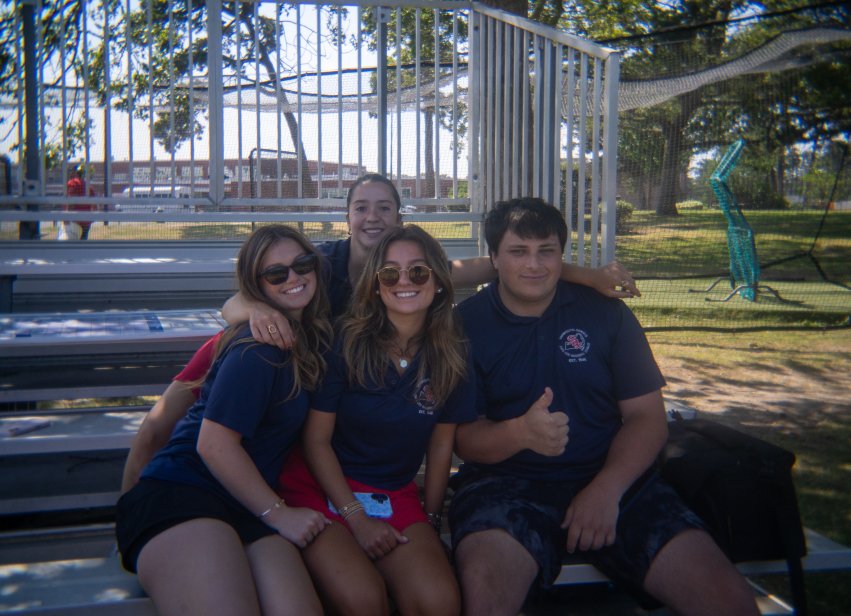 Four interns pose together on bleachers at a baseball field.