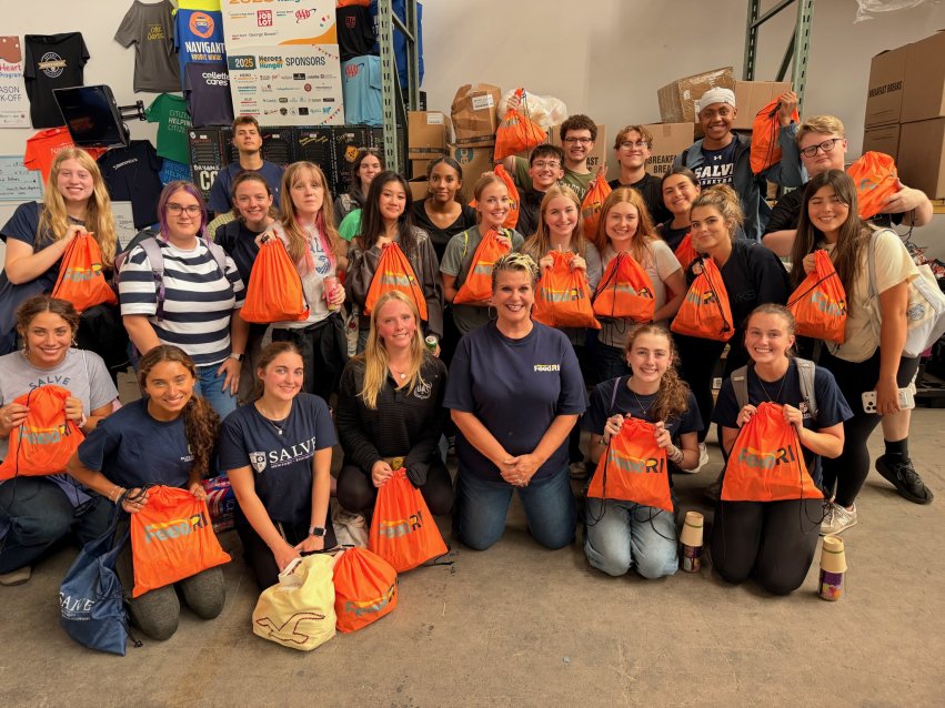 Salve students and staff hold orange FeedRI bags during a volunteer service project.