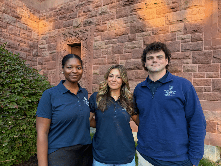 Three Salve student leaders pose together outside a stone campus building.