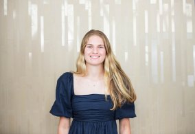 Blonde female student in blue dress, smiling