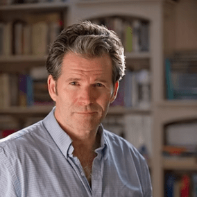 Professional headshot of Andre in front of bookshelf.