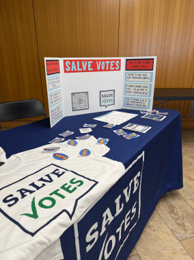 SalveVotes information table featuring voter registration resources, stickers and T-shirts.