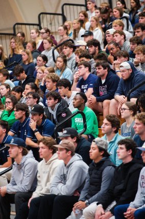 Student athletes in bleacher seats intently listening and looking forward.