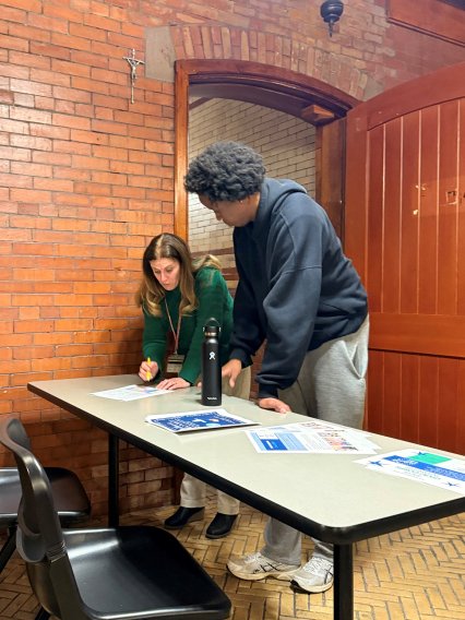 Professor and student stand over a desk and discuss a paper