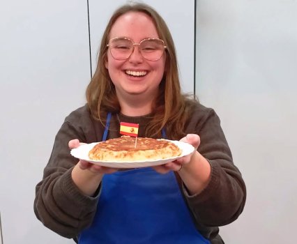 Koenig smiling holding a pancake with a small Spain flag in it.