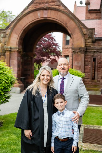 Mother, father and son pose at graduation in front of stone archway