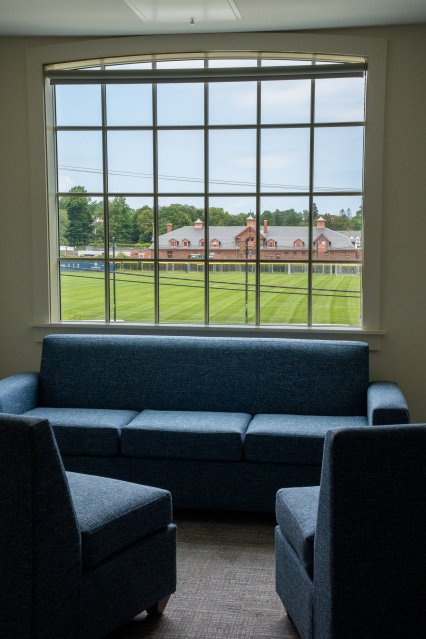 view of a field through a large window with a sofa underneath