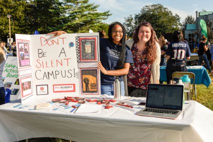 Two female students displaying a poster at a table