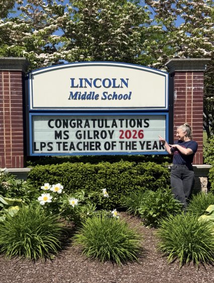 Teacher points to Lincoln Middle School sign announcing her as 2026 Teacher of the Year.