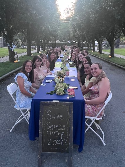 Service Plunge participants gather around a long outdoor table for a closing dinner.